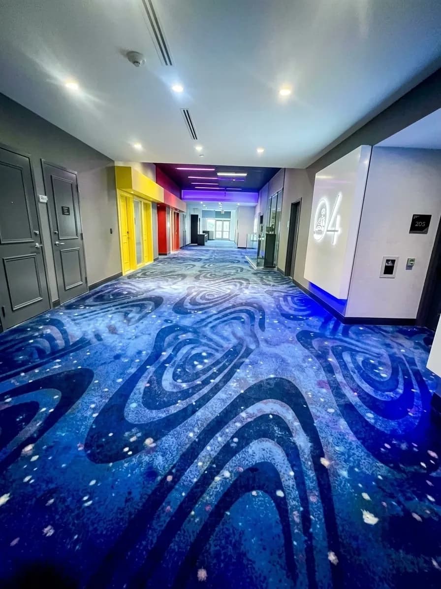Commercial corridor with a patterned blue carpet freshly cleaned under recessed lighting