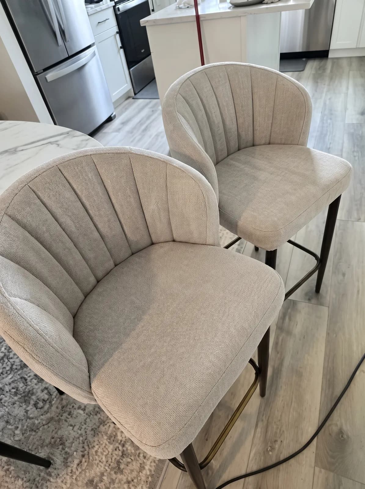 Two cream channel-tufted upholstered bar stools freshly cleaned in a bright kitchen